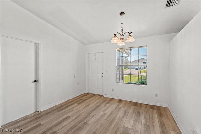 unfurnished room featuring an inviting chandelier and light wood-type flooring