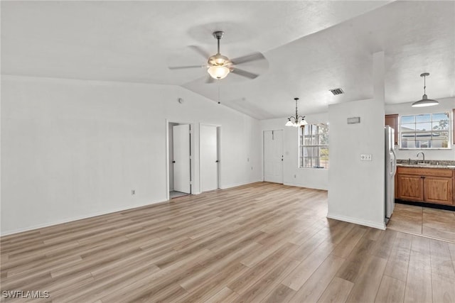 unfurnished living room with ceiling fan with notable chandelier, sink, vaulted ceiling, and light hardwood / wood-style floors