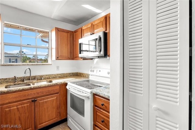 kitchen featuring light tile patterned flooring, sink, white electric range oven, and light stone counters