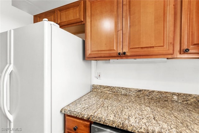 kitchen featuring light stone countertops and white refrigerator