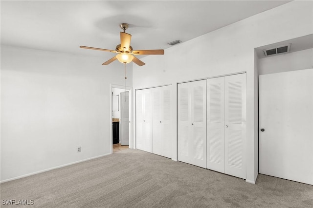 unfurnished bedroom with light carpet, ceiling fan, ensuite bath, and multiple closets