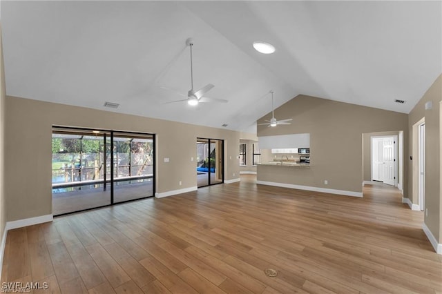 unfurnished living room featuring ceiling fan, high vaulted ceiling, sink, and light wood-type flooring