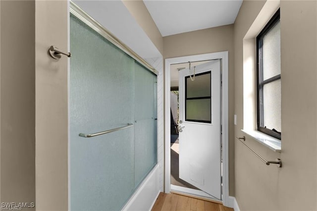 bathroom featuring hardwood / wood-style flooring and shower / bath combination with glass door