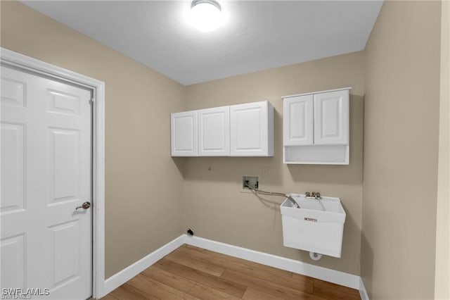 laundry room featuring sink, hookup for a washing machine, light hardwood / wood-style floors, and cabinets