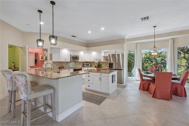 kitchen with pendant lighting, appliances with stainless steel finishes, kitchen peninsula, and white cabinets