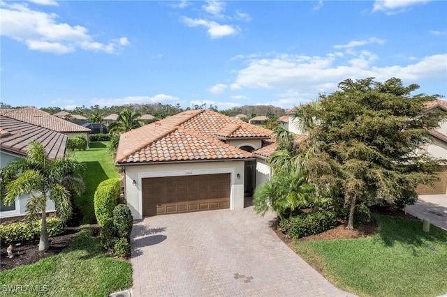 mediterranean / spanish home featuring stucco siding, an attached garage, driveway, a tiled roof, and a front lawn