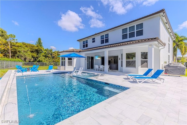 rear view of house with pool water feature, a fenced in pool, and a patio area