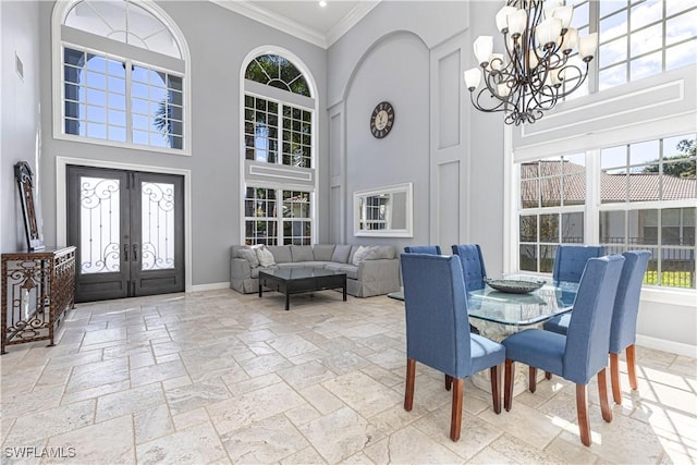 dining space featuring an inviting chandelier, crown molding, french doors, and a high ceiling