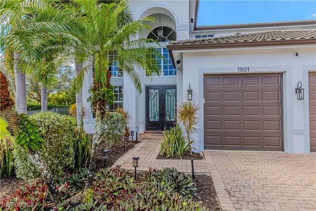 1801 Senegal Date Dr, Naples, FL 34119 - entrance to property with french doors, stucco siding, decorative driveway, and an attached garage