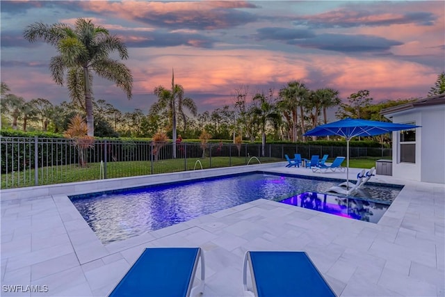 pool at dusk with a patio and pool water feature