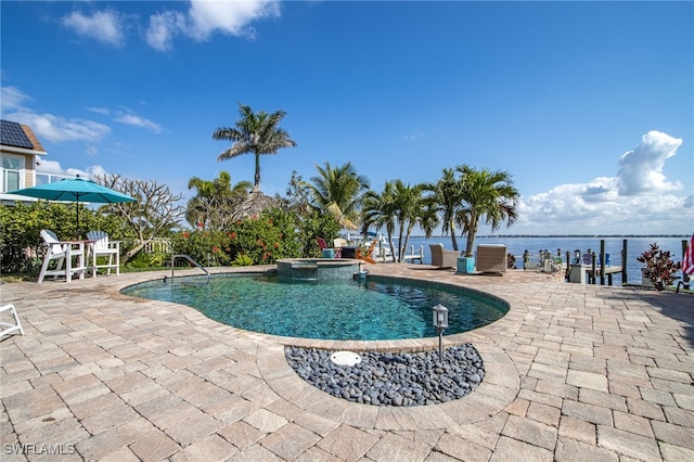 view of swimming pool featuring a water view, a patio area, and a pool with connected hot tub