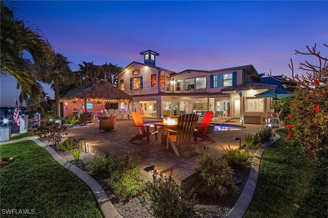 back house at dusk with a patio and a balcony