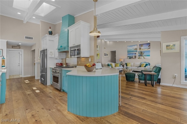 kitchen with a skylight, custom exhaust hood, stainless steel appliances, visible vents, and white cabinetry