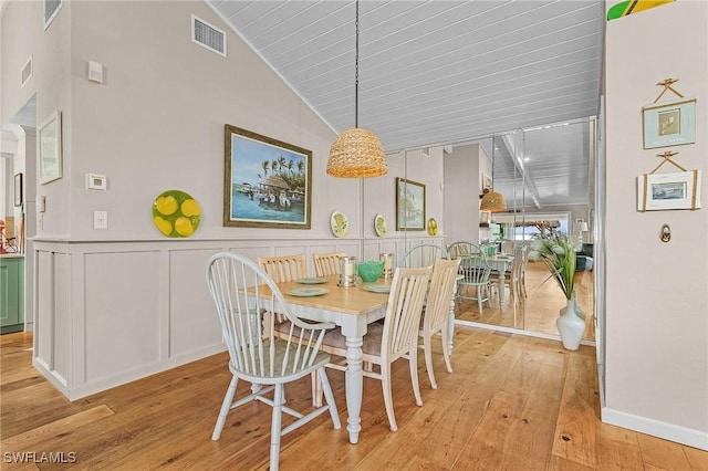 dining space with light wood-style floors, wainscoting, visible vents, and a decorative wall