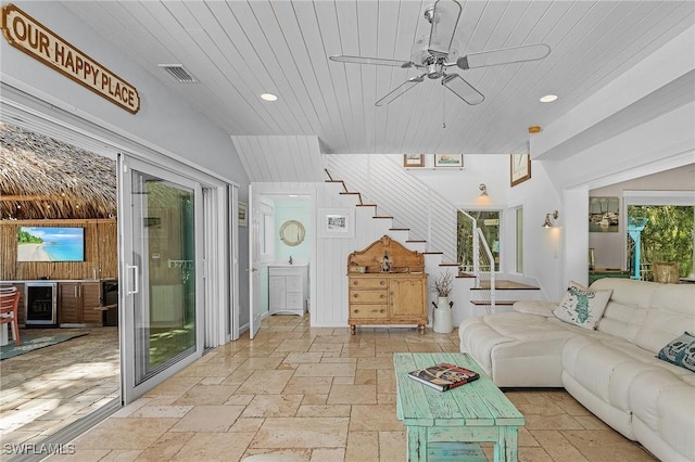 unfurnished living room featuring ceiling fan, wine cooler, wooden ceiling, stairway, and stone tile flooring