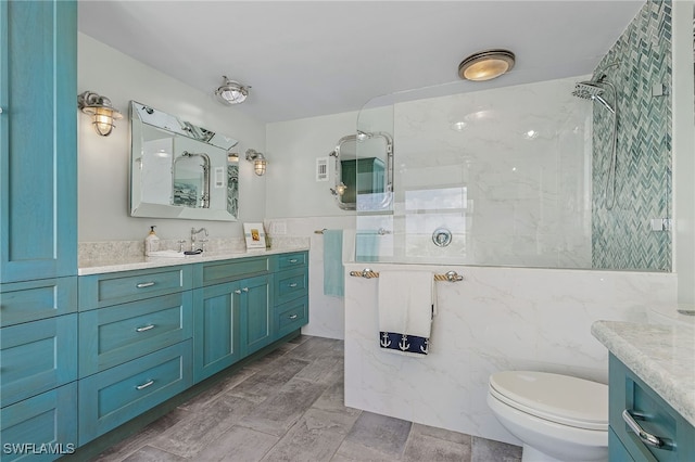 bathroom featuring toilet, tile walls, a marble finish shower, and vanity