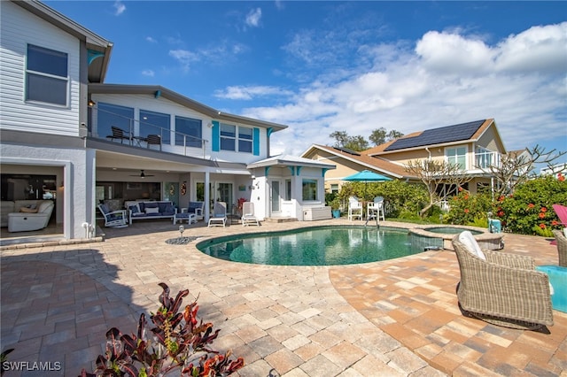 view of pool featuring a patio, a pool with connected hot tub, an outdoor living space, and a ceiling fan