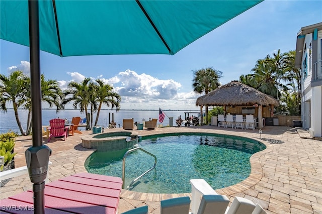 view of swimming pool with outdoor dry bar, a patio, a water view, and a pool with connected hot tub