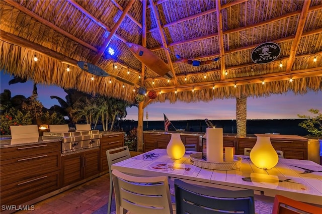 patio terrace at dusk featuring a gazebo, outdoor dining space, and area for grilling