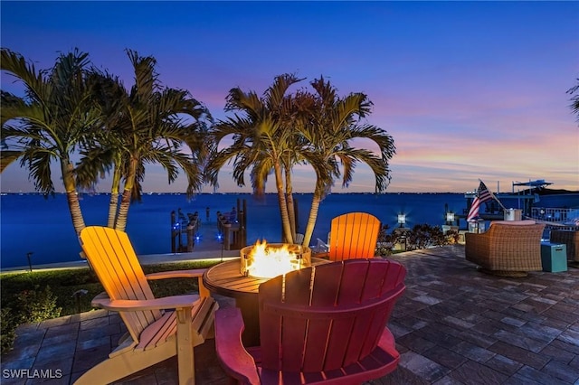 patio terrace at dusk with a water view and a fire pit