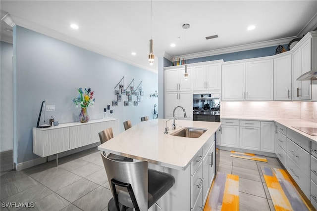 kitchen with pendant lighting, sink, a kitchen island with sink, and white cabinets