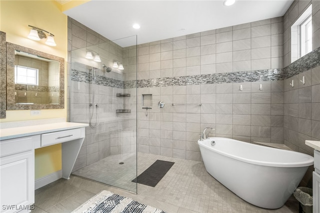 bathroom featuring vanity, plus walk in shower, tile patterned flooring, and tile walls