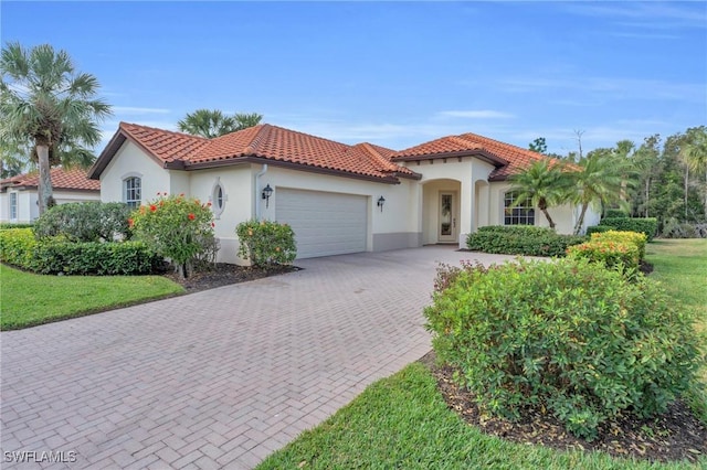 12560 Wildcat Cove Cir, Estero, FL 33928 - mediterranean / spanish house with a garage, stucco siding, decorative driveway, a tiled roof, and a front lawn