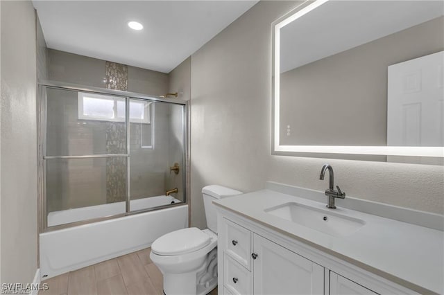 full bathroom with enclosed tub / shower combo, vanity, and toilet