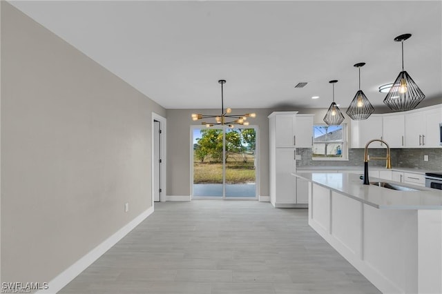 kitchen featuring sink, decorative backsplash, decorative light fixtures, and white cabinets