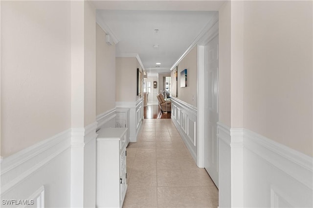 hallway with light tile patterned floors and ornamental molding