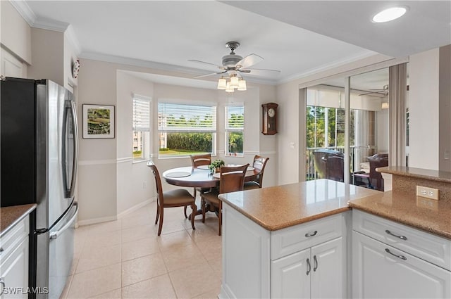 kitchen with light tile patterned floors, ornamental molding, stainless steel fridge, ceiling fan, and white cabinets