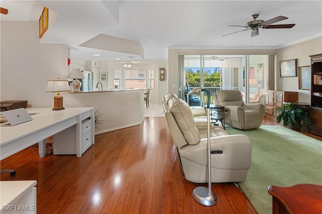 living room with hardwood / wood-style flooring, crown molding, sink, and ceiling fan