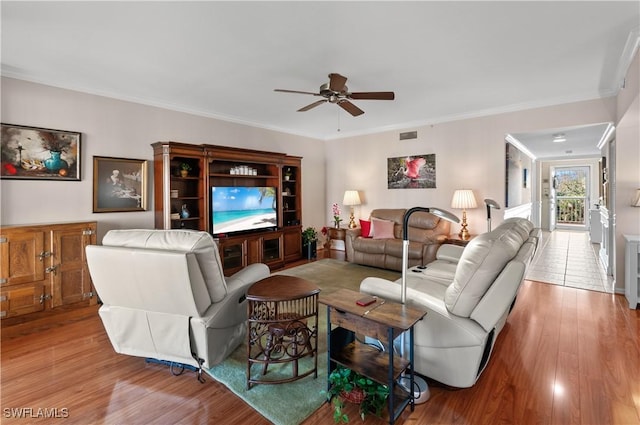 living room featuring crown molding, ceiling fan, and light wood-type flooring