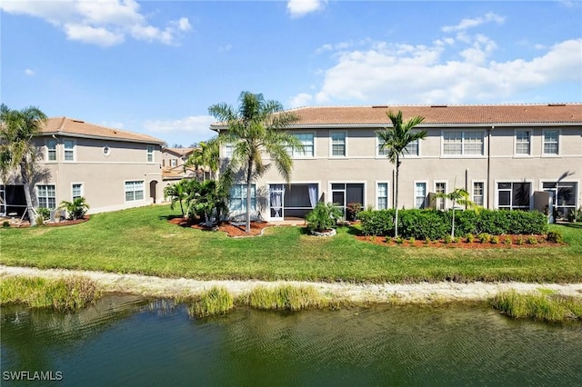 back of house with a water view and a yard