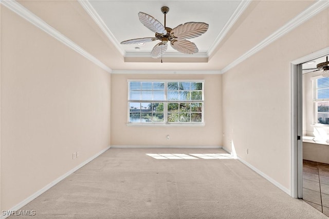 carpeted spare room with ornamental molding, a raised ceiling, and ceiling fan