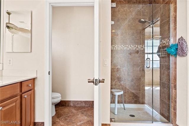 bathroom with vanity, a shower with door, and toilet