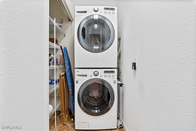 washroom with stacked washing maching and dryer and tile patterned floors