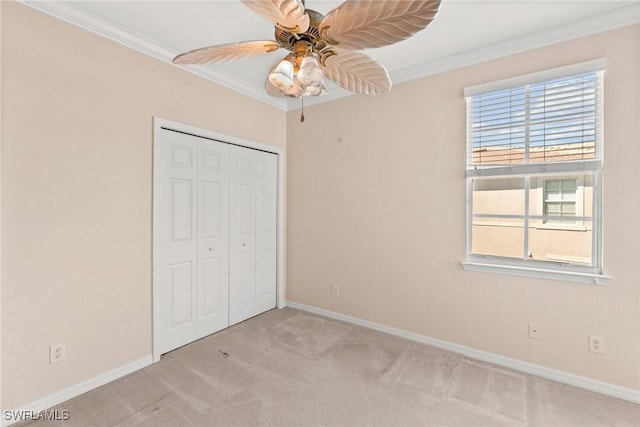 unfurnished bedroom with crown molding, light colored carpet, ceiling fan, and a closet