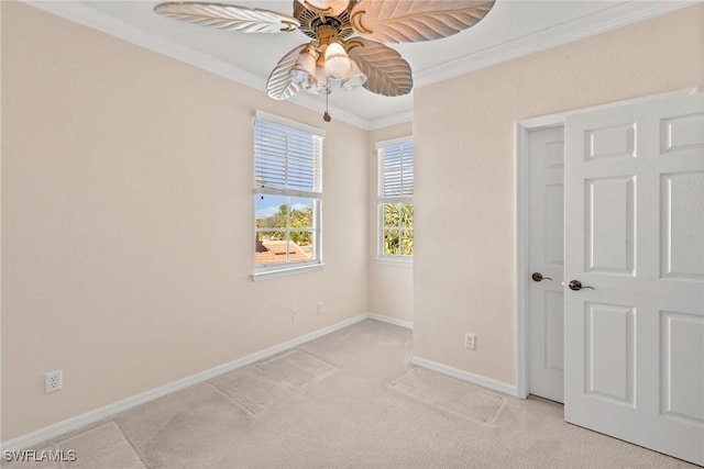 empty room with ceiling fan, light colored carpet, and ornamental molding