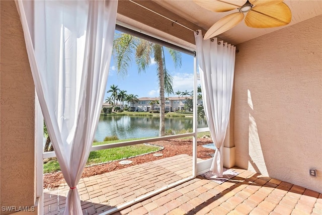 unfurnished sunroom featuring ceiling fan and a water view