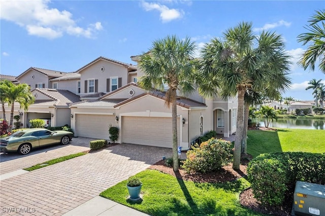 mediterranean / spanish-style home featuring a water view, a garage, and a front yard