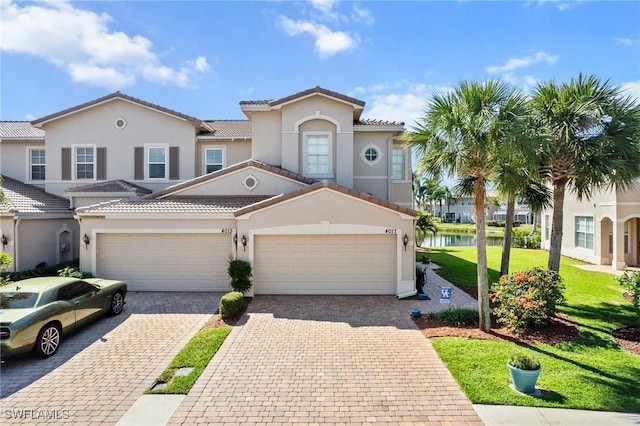 mediterranean / spanish house featuring a water view, a garage, and a front lawn