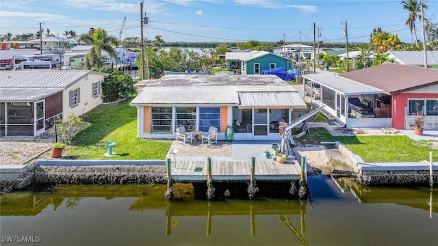 back of property featuring a water view, a patio, a sunroom, and a lawn