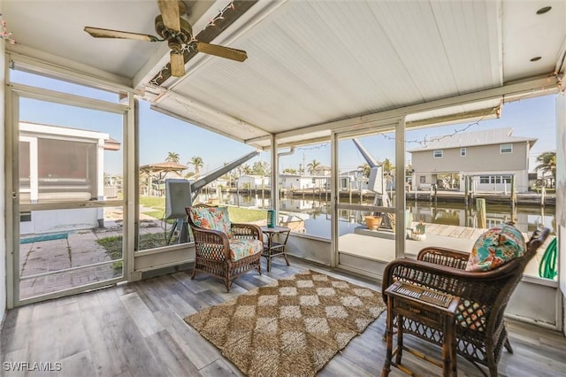 sunroom featuring plenty of natural light, ceiling fan, and a water view