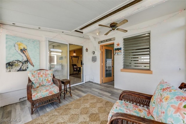 sitting room featuring ceiling fan, hardwood / wood-style floors, and beam ceiling