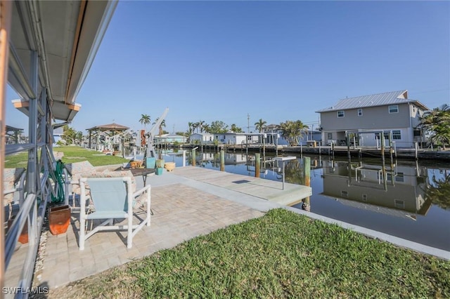 view of dock featuring a yard, a patio area, and a water view