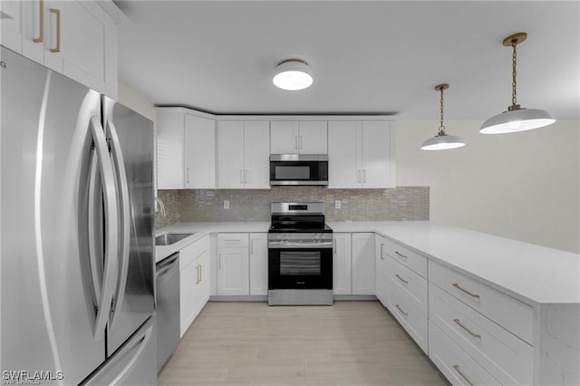 kitchen with tasteful backsplash, white cabinetry, appliances with stainless steel finishes, and pendant lighting