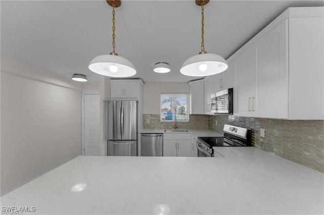 kitchen with pendant lighting, sink, white cabinetry, stainless steel appliances, and tasteful backsplash