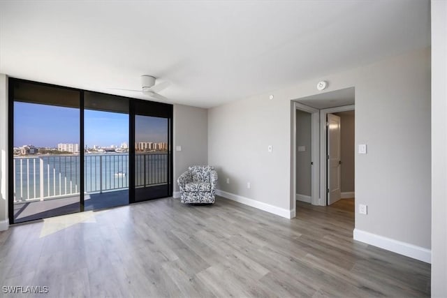 unfurnished room featuring ceiling fan, floor to ceiling windows, and hardwood / wood-style floors