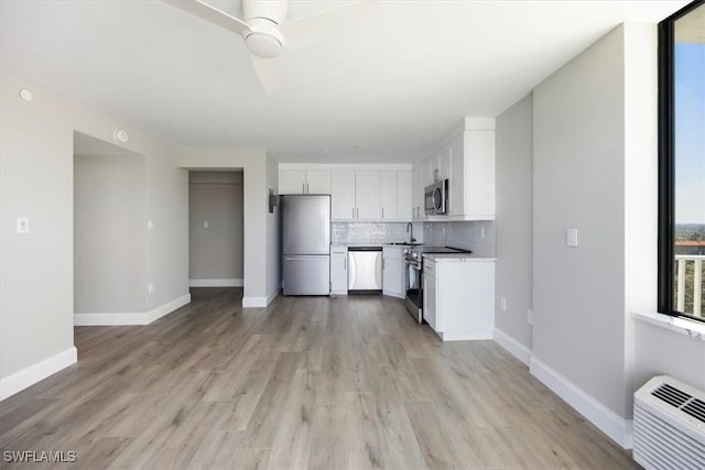 kitchen featuring white cabinetry, a wall mounted air conditioner, stainless steel appliances, light hardwood / wood-style floors, and decorative backsplash